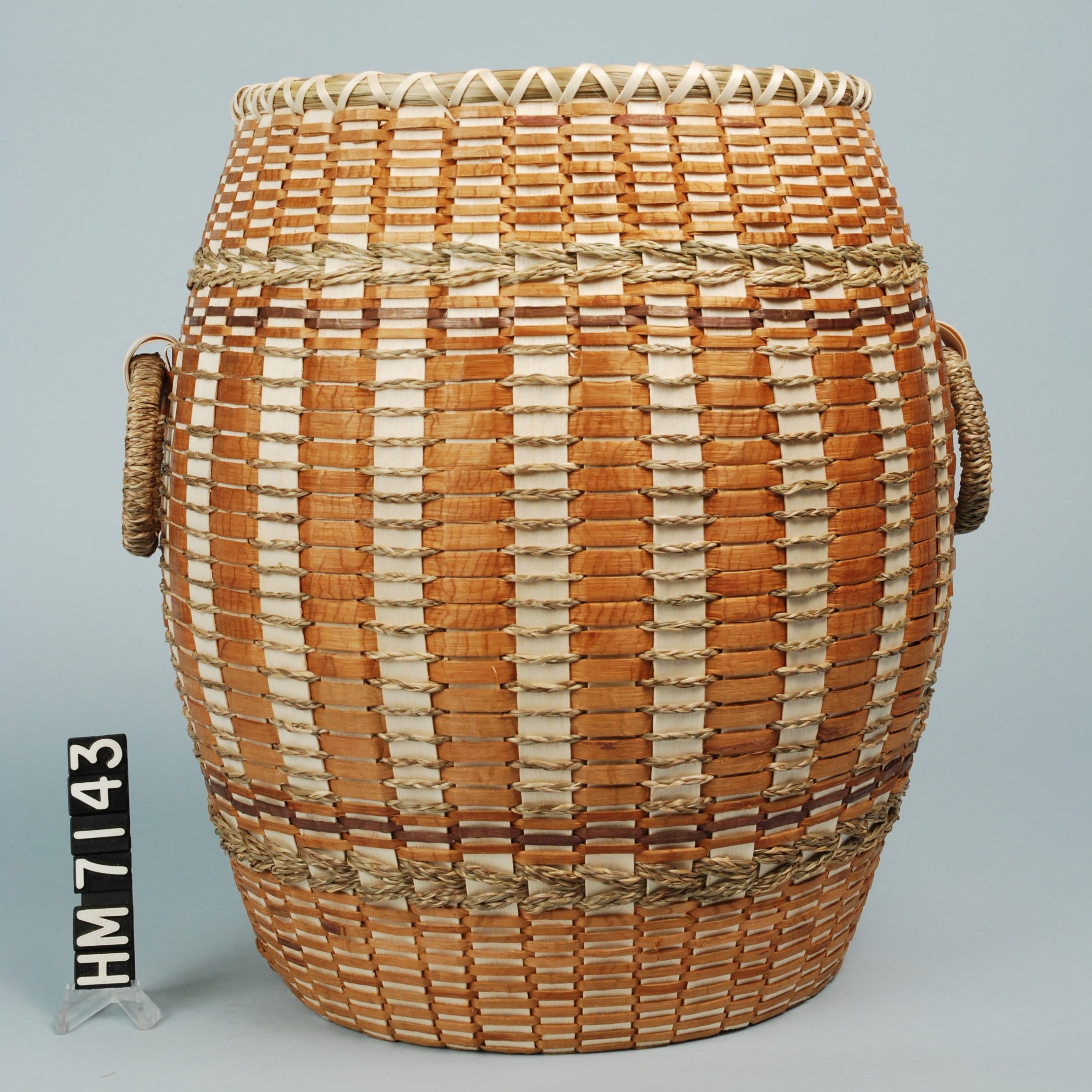 Image of barrel-shaped basket with cedar weavers and braided sweetgrass details.