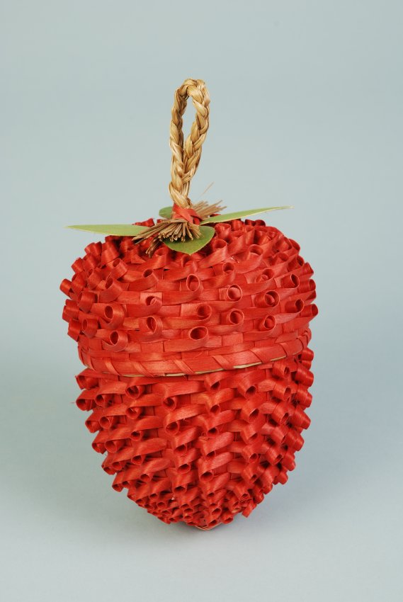 Image of basket shaped like bright red strawberry with braided grass handle.