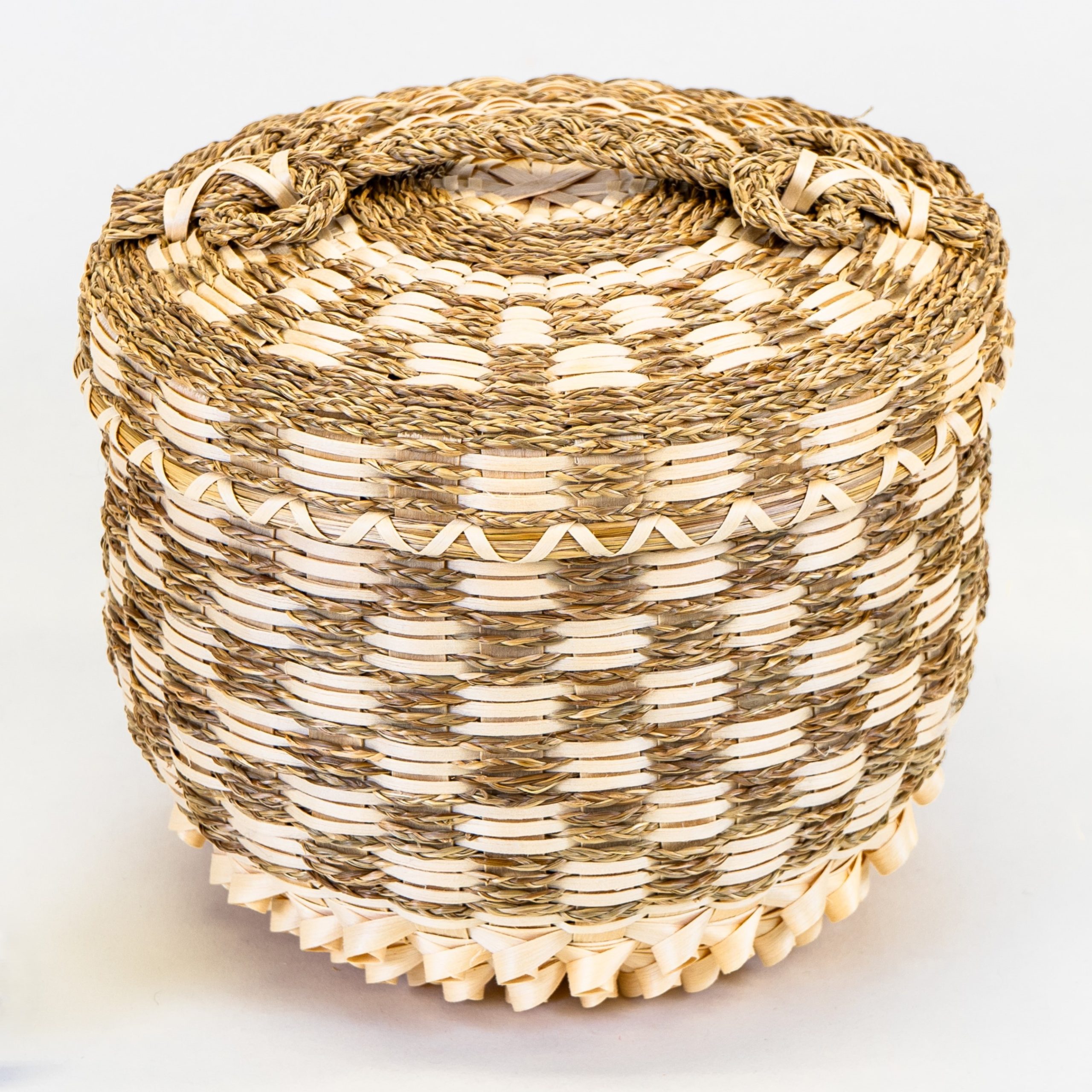 Image of a small, intricate basket with sweetgrass braids woven in to create a checkered pattern.