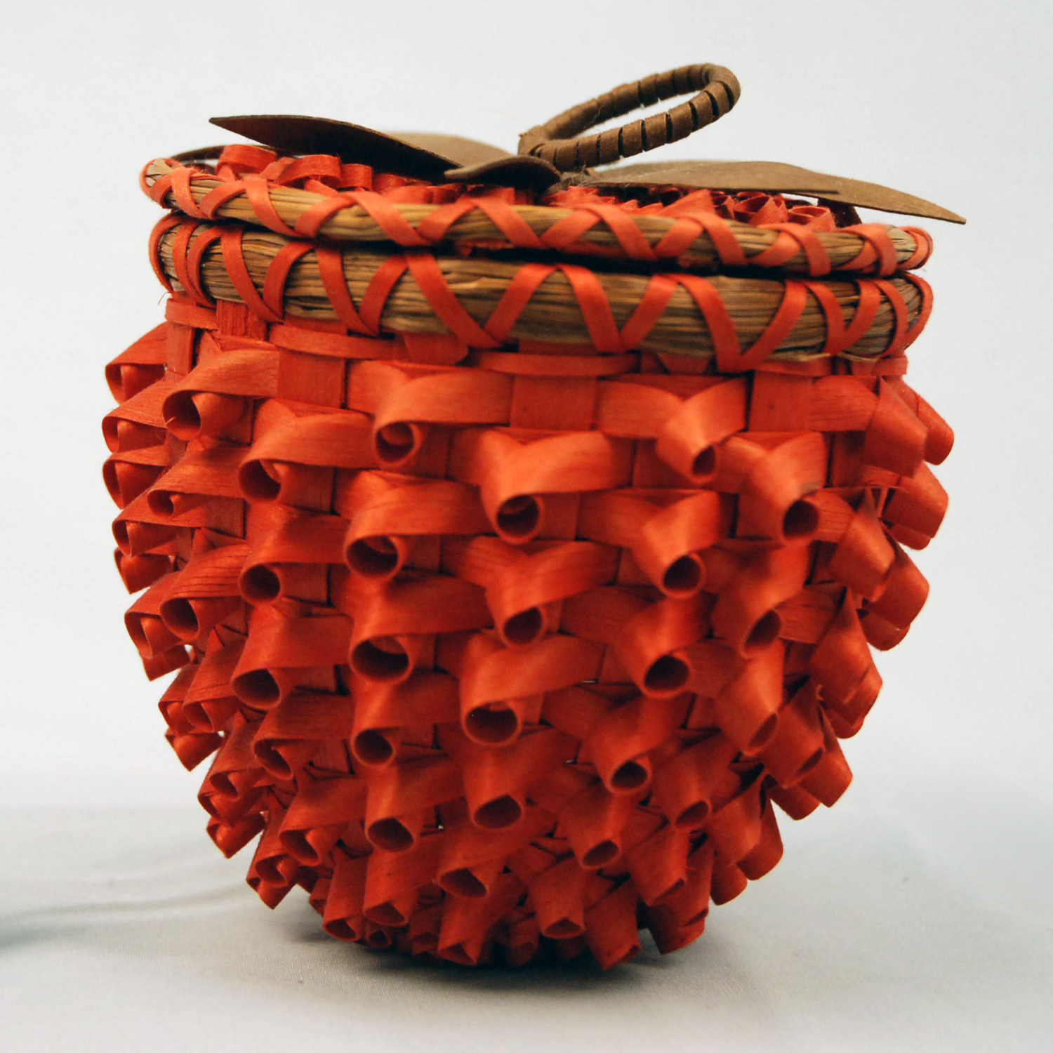 Image of small basket shaped as a strawberry with bright red curls.