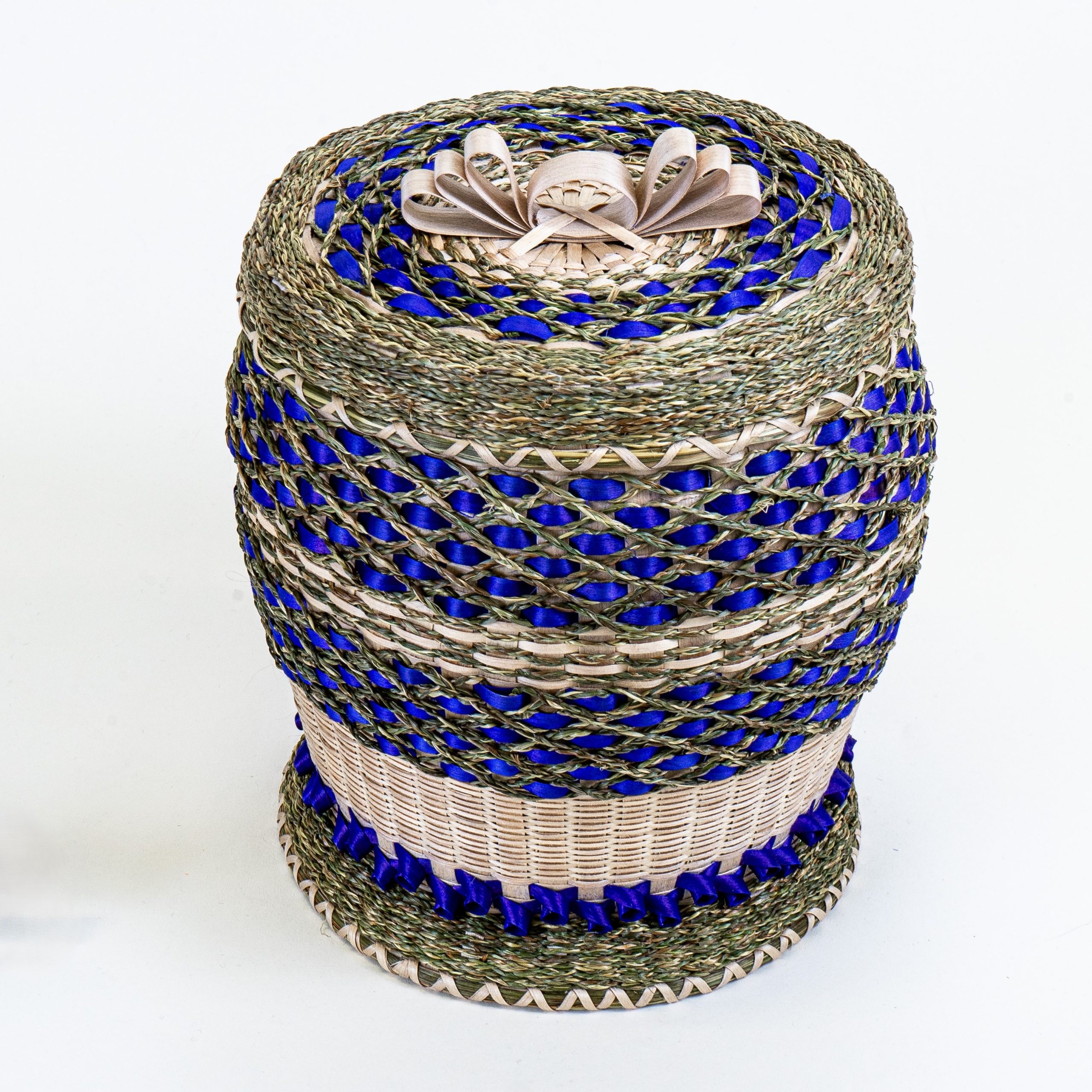 Image of intricate basket with bright violet and braided sweetgrass details and brown ash bow on cover.