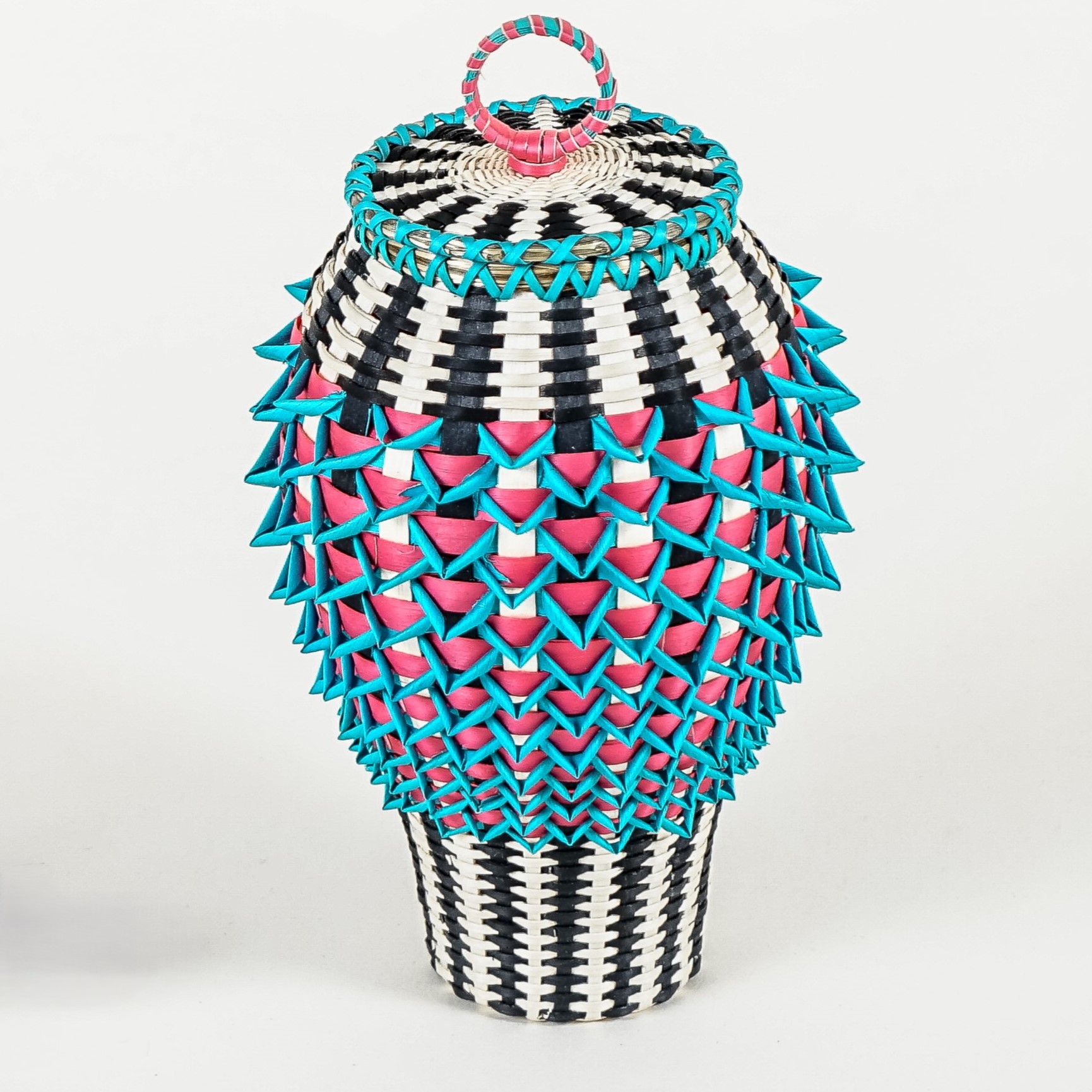 Basket, narrow at base, then widening to rounded shape at shoulder. Areas of light and black stripes. The middle has teal points offset with bright magenta beneath.