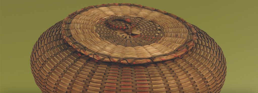 Detail image of a wide, rounded basket with cover woven with single strands of sweetgrass.