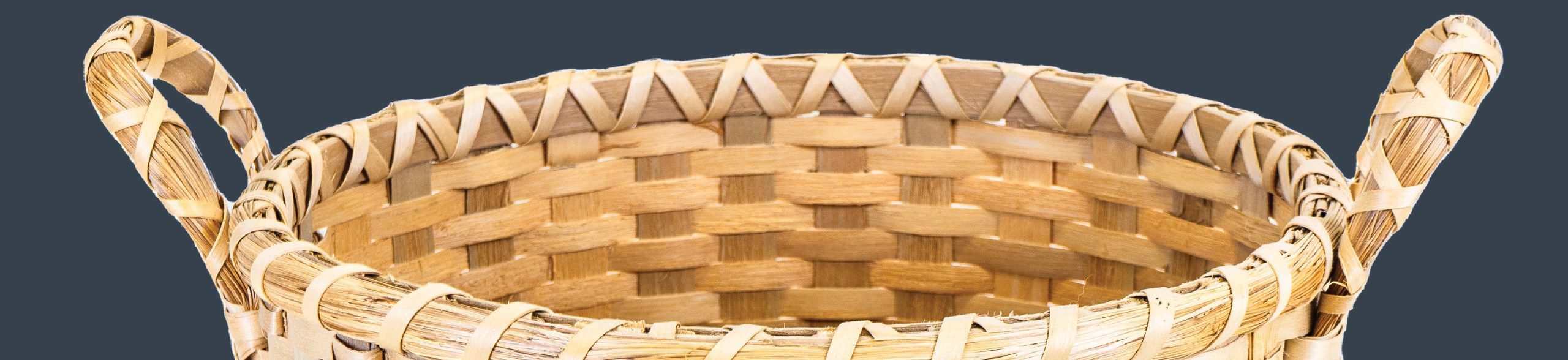 Detail image of the top of a basket with wrapped sweetgrass handles.