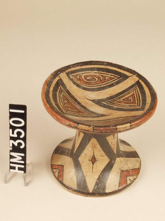 Miniature polychrome ceramic pedestal plate. "Y" element animal kennings adorn the four paneled sections. The sections are positioned in a manner suggesting the heads and tails of two "Y" shaped elements.