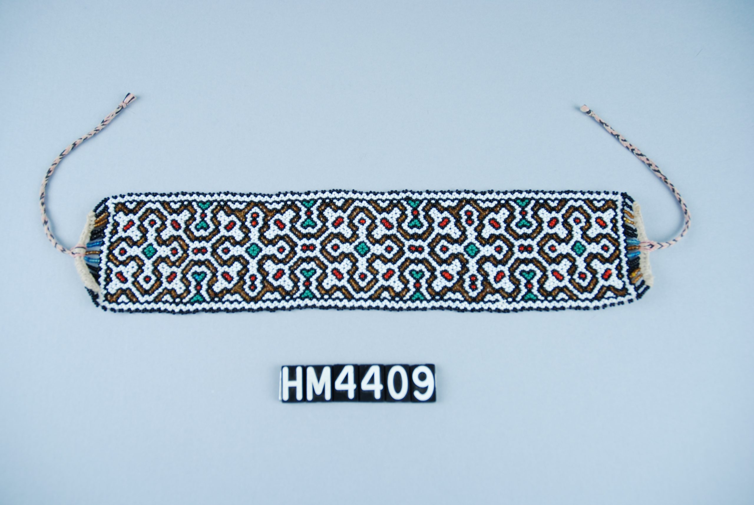 Image of wide beaded bracelet with white, black, teal, red, and gold beads.