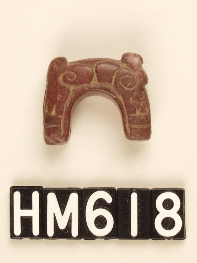A small carved stone object in the form of a half of a ring, shaped like a small animal.