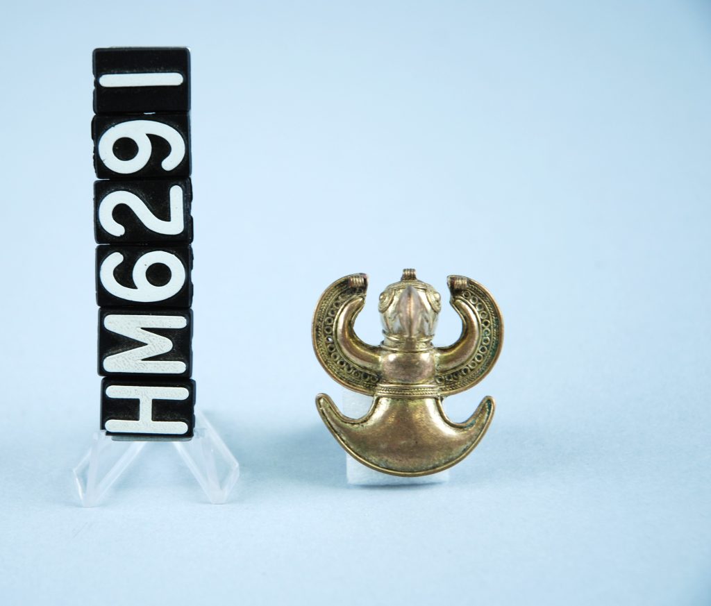 Image of small golden ornament in the shape of a bird with wings spread.