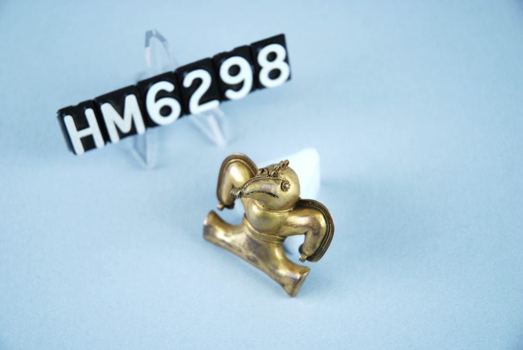 Image of small golden ornament in the shape of a bird with wings spread.