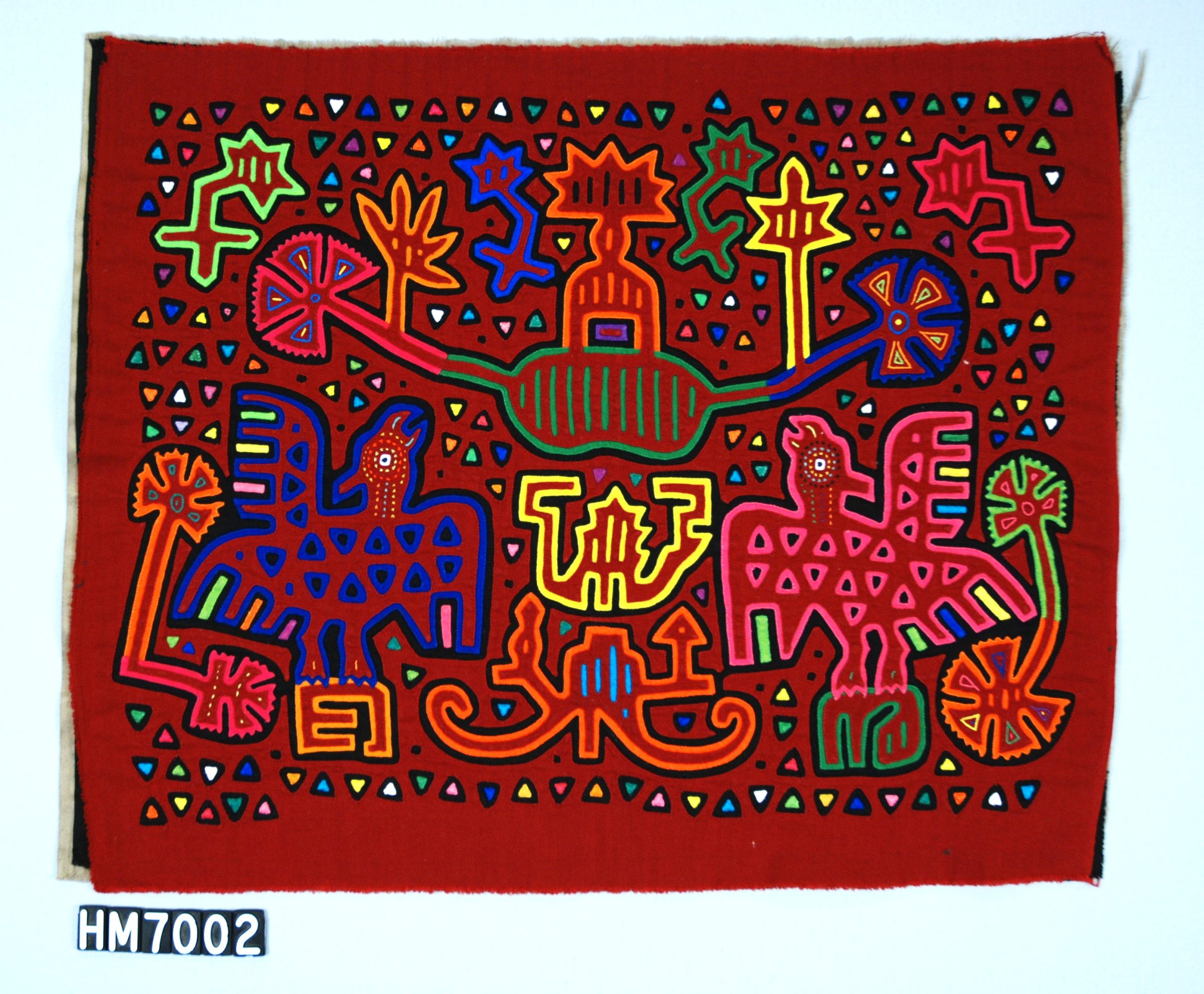 Rectangular red fabric with two birds and plant motifs and a background of triangles.