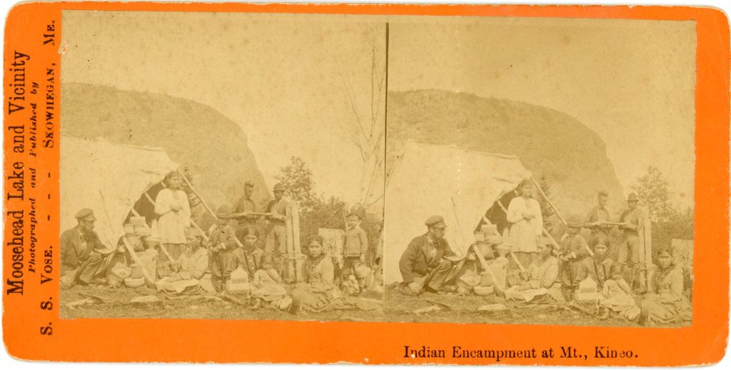 Two offset sepia-tone images of a group of people by a tent with a mountain in the background. The people are holding or displaying baskets and birchbark canoes.