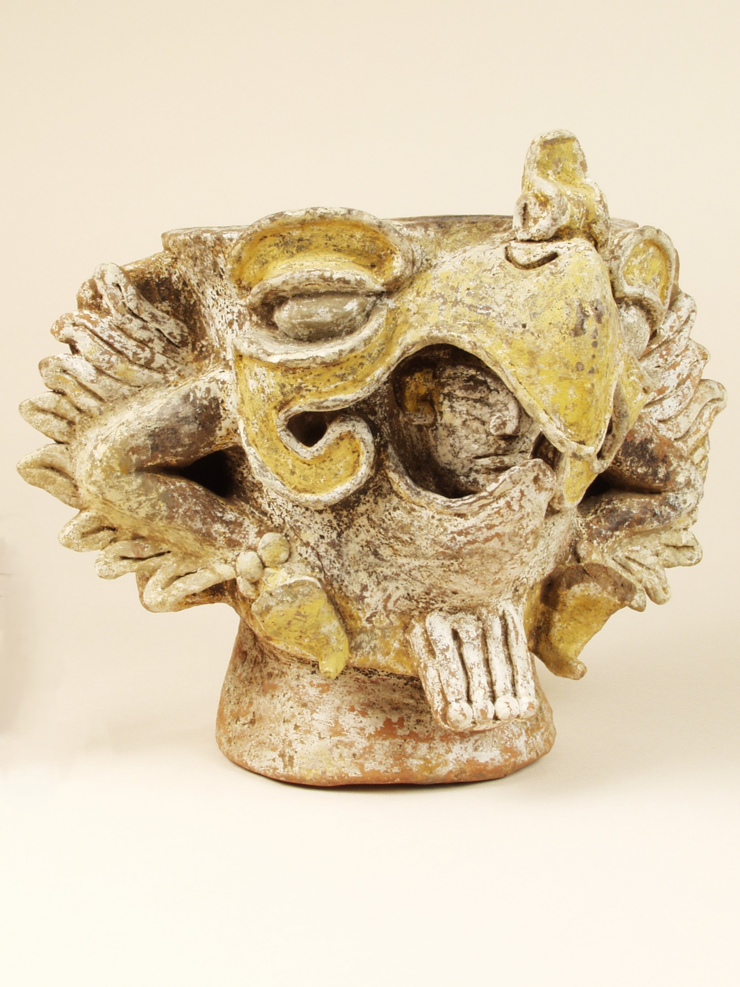 Ceramic vessel in the shape of a bird head with a man peaking out inside the slightly open beak. Beak is painted yellow.