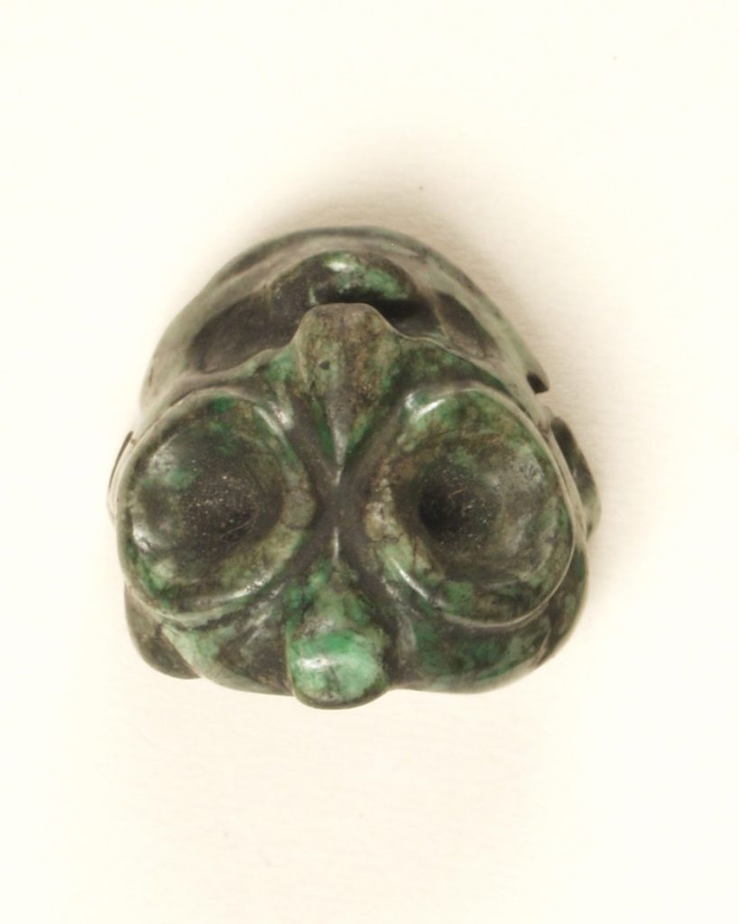 Small greenstone bead in the shape of an owl with large eyes.