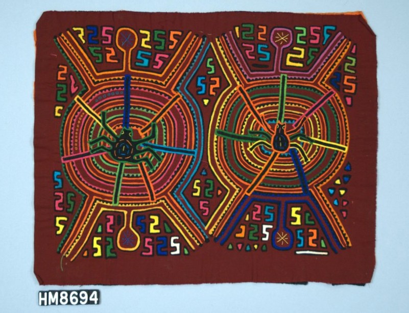 Rectangular fabric with colorful depictions of two spiders on webs against a background of "s" shapes.