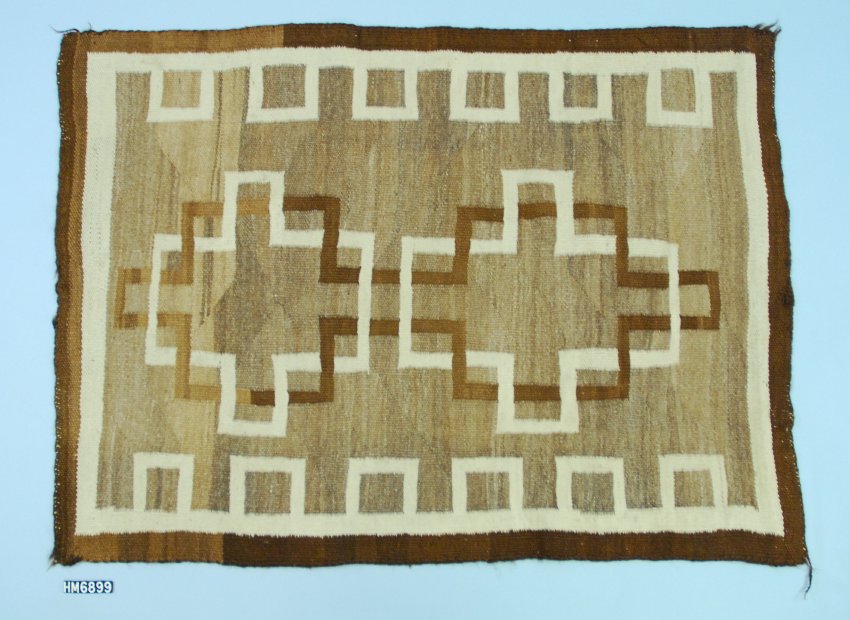 Woven textile in cream, tan, and brown. Interlinked patterns of angular lines and boxes.