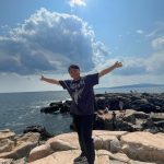 IEI student standing on a rock, arms outstretched