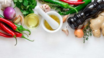 Image including various spices, peppers, vegetables, oils, and cooking supplies.