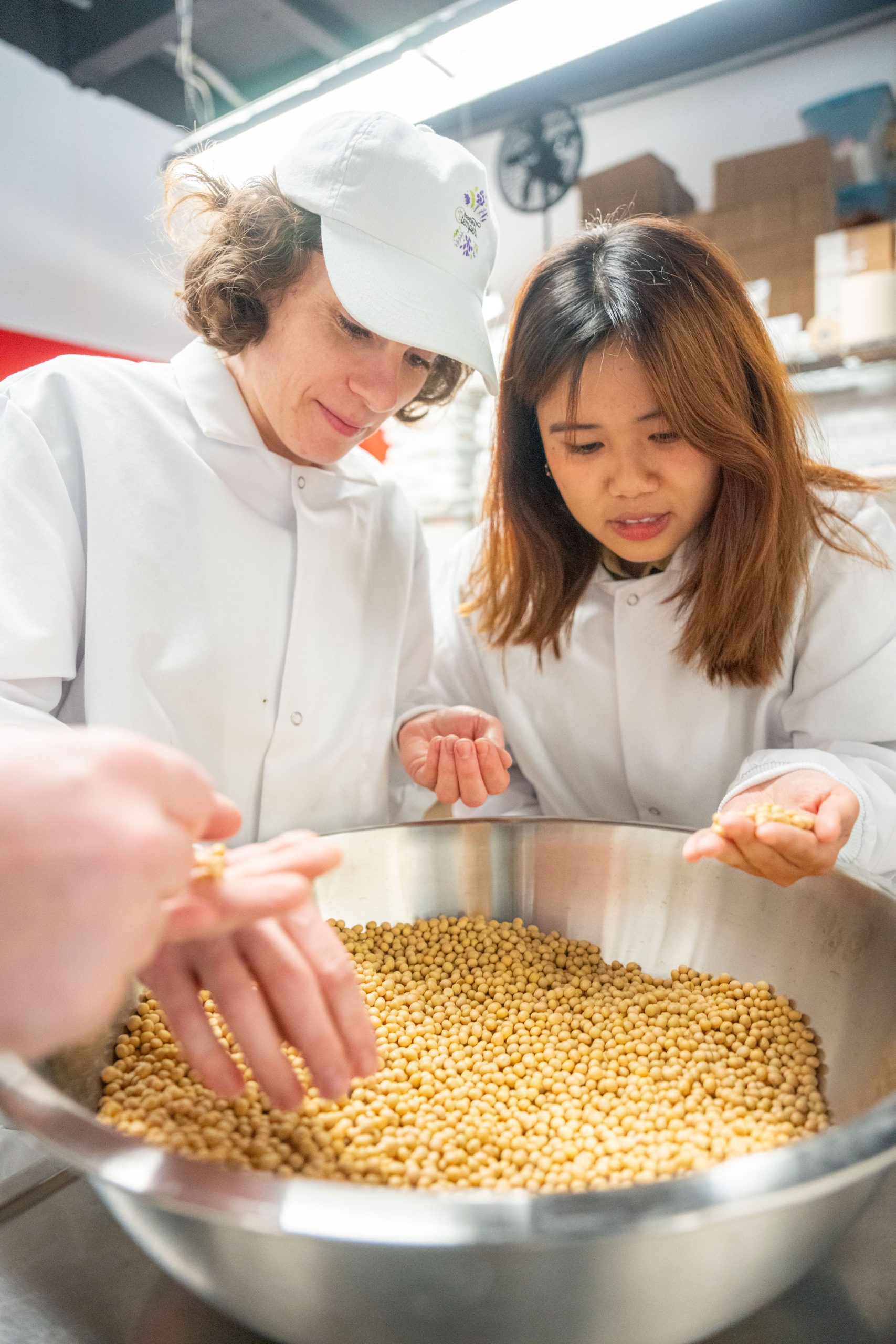 Two young people in chef's jackets work with a bowl of grain.