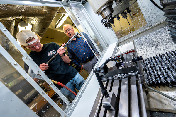 A student at UMaine's Advanced Manufacturing Center works on a machine