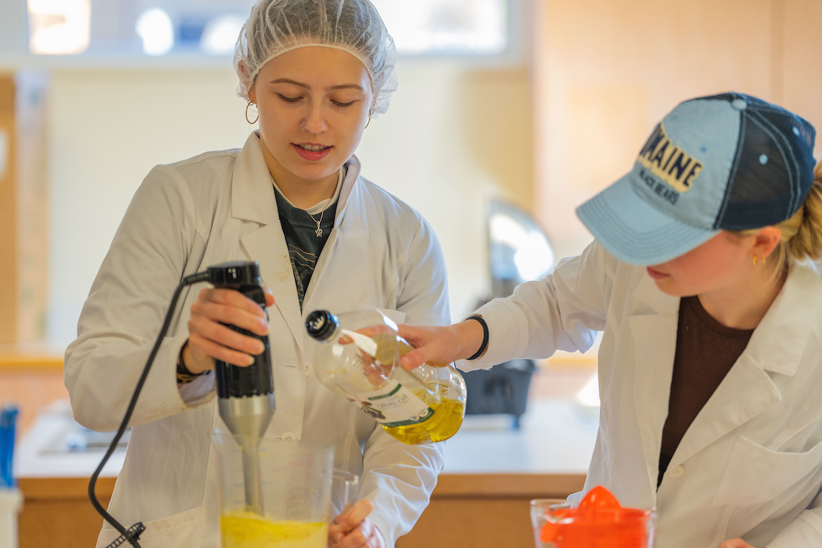 Two students prepare and cook pasta with meatballs in the UMaine's Hitcher Food Pilot Plant