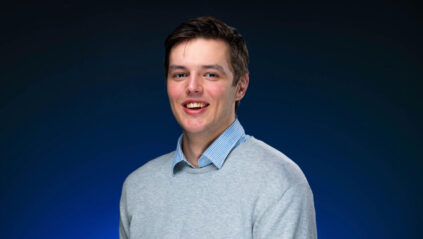 picture of Vilgot standing in front of blue background, smiling