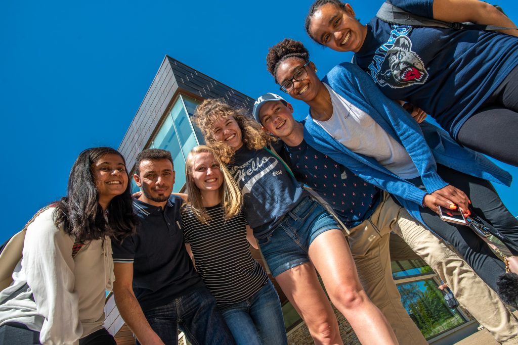 Group of college students looking down at camera and smiling