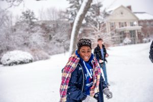 A snowy scene of an international student on the University of Maine campus.
