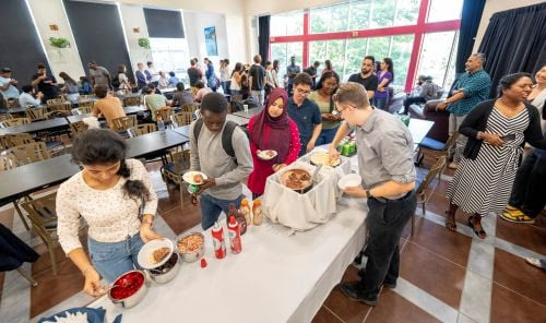 Students in line next to a table being served drinks in the North Pod