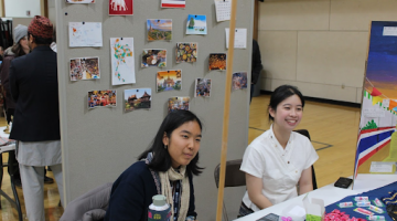 Two students sitting at booth table, presenting cultural information