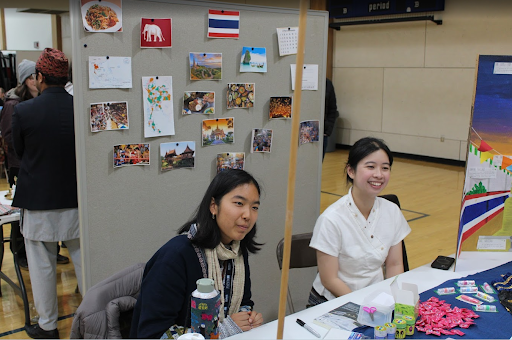 Two students sitting at booth table, presenting cultural information
