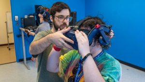 Photo from New Student Orientation of one of our incoming students working with a graduate research assistant in Justin Dimmel's VR lab