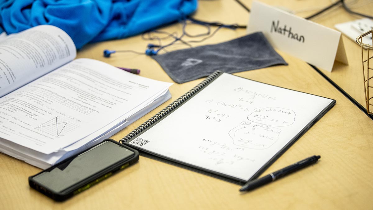 A photo of a notebook, textbook and calculator on a table