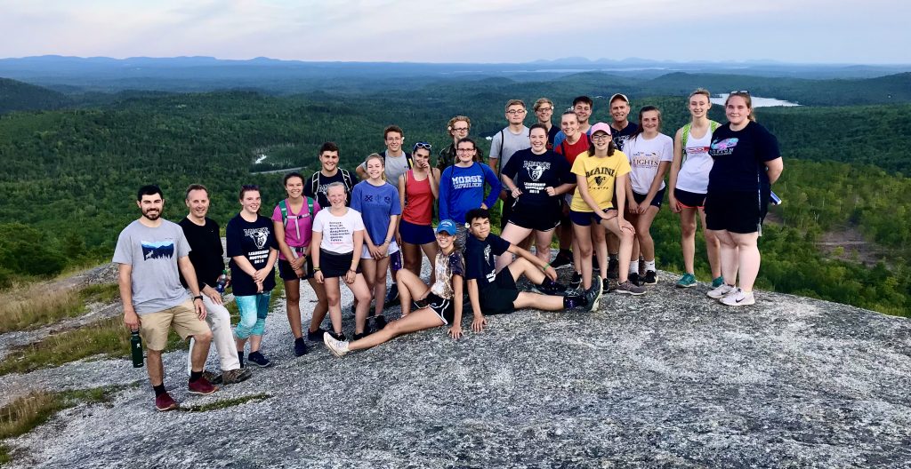 Group photo of leadership team atop an outdoor rocky peak 