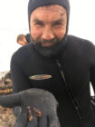 Rick Wahle in scuba gear holding a baby lobster