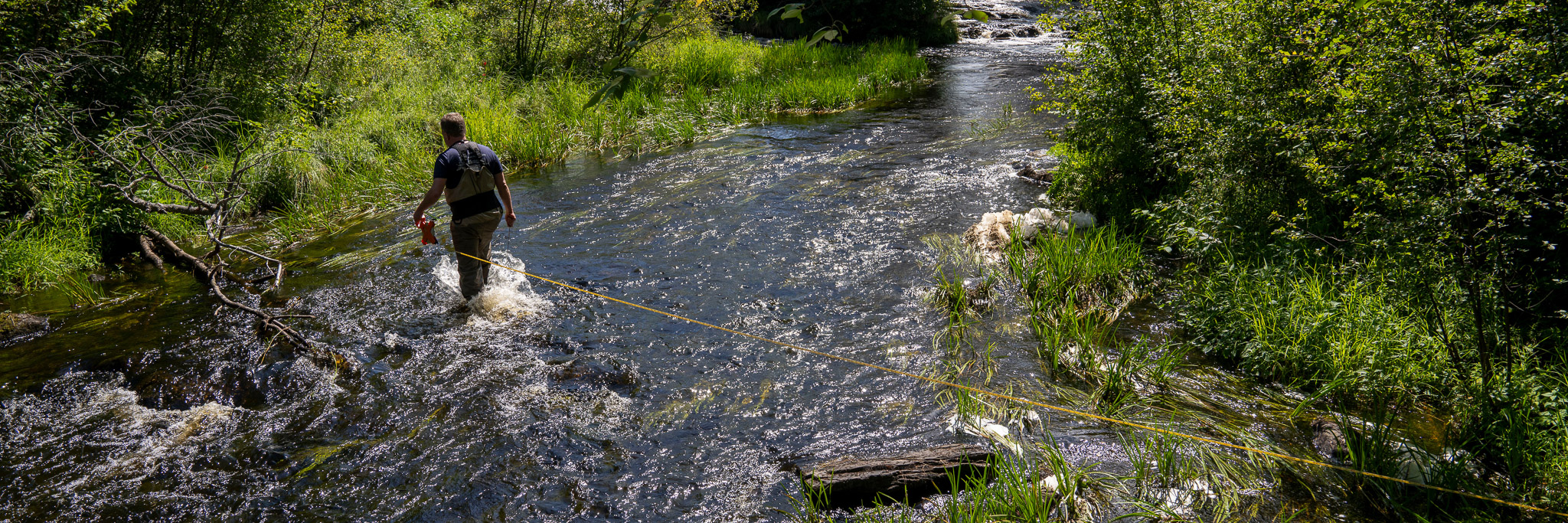 photo of person bringing rope across stream
