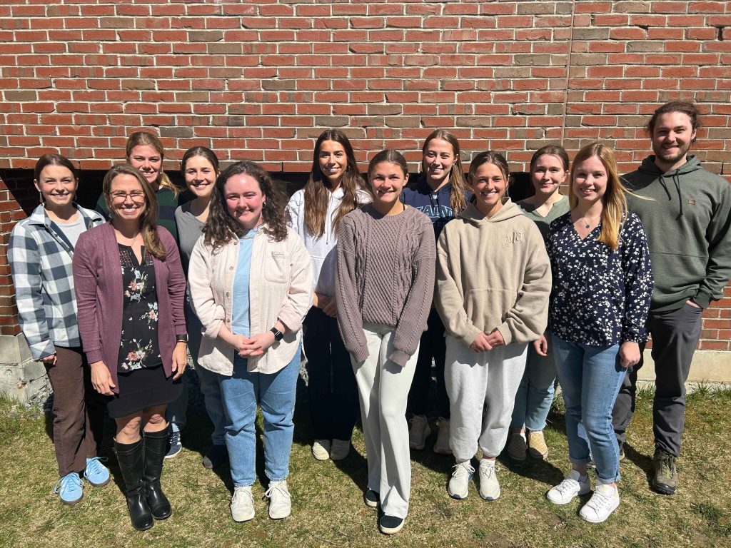 Dr. Maginnis, 4 graduate students, and 7 undergraduate students stand outside at UMaine