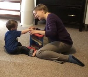 Early Interventionist playing on floor with young child w ASD
