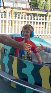 Young boy smiling with headphones on amusement ride