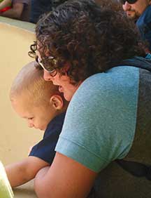 Mom with arms around young son, looking into animal pen