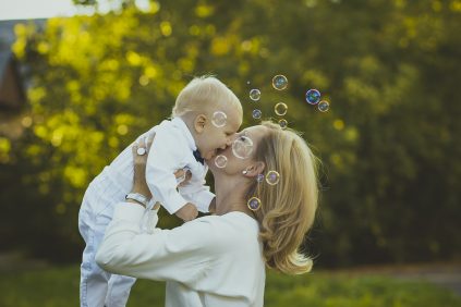 Mother lifting infant into the air and kissing