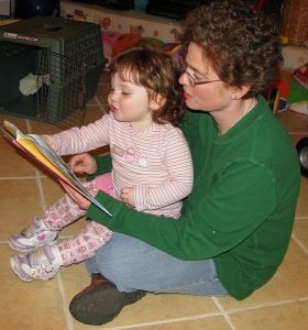 Woman reading a book to young child on her lap