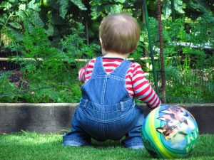 Young child looking at garden with ball at his feet