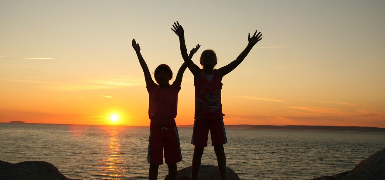 Two young children on beach at sunset