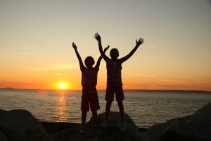 Two young children on beach at sunset