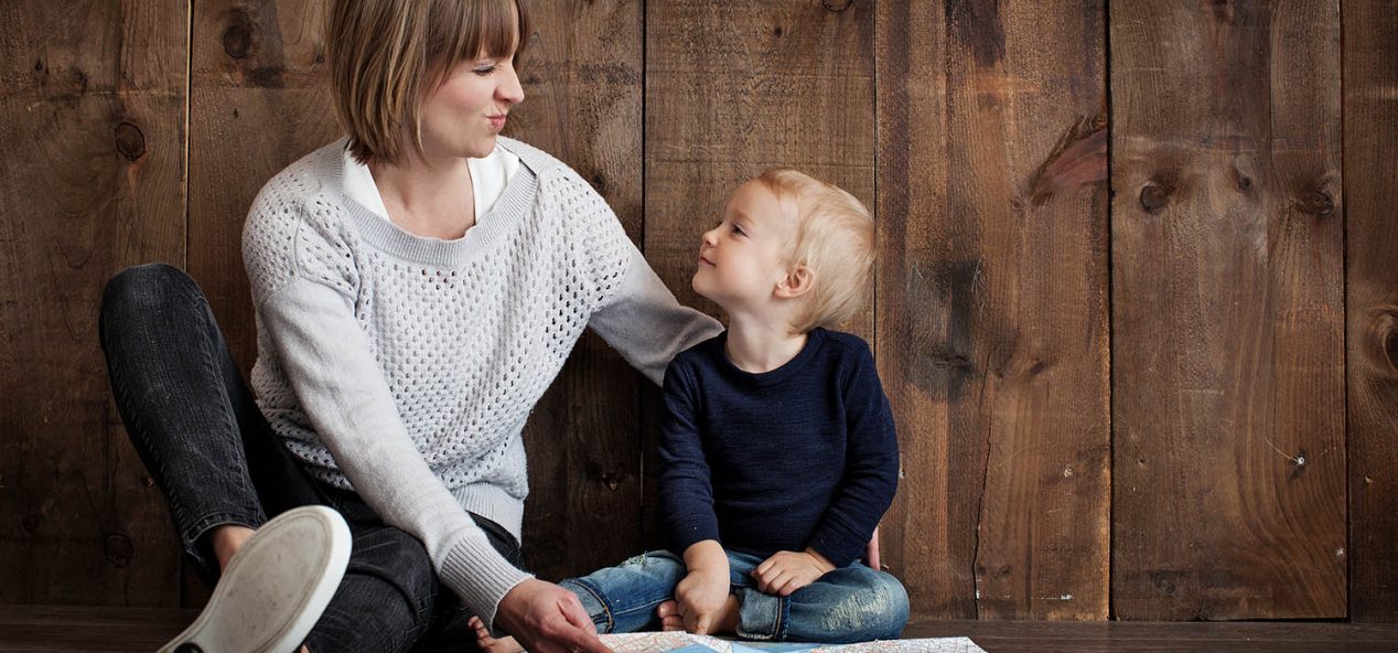 Mother and child sitting on floor looking at each other