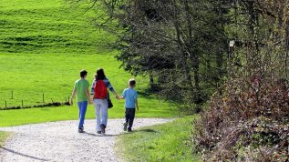 Mother and two sons holding hands walking down a gravel path