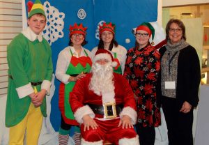 Santa seated with elves behind him