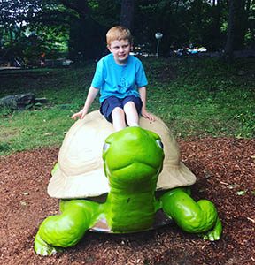 Boy sitting atop a giant turtle statue