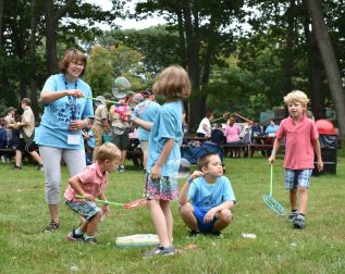 Young children blowing bubbles in field