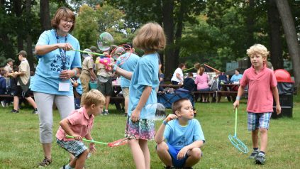 Young children blowing bubbles in field